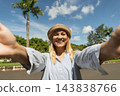 Woman happily greets camera with sunny skies above 143838766
