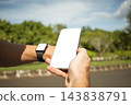 Person using smartphone with smartwatch on wrist in natural setting 143838791