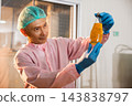 A male worker dressed in a uniform and gloves inspects Basil seed products on the conveyor belt 143838797