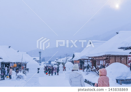 2月中旬，冬日的景象，大內宿的街道兩旁擺放著各種雪雕，還有茅草屋頂的房屋和熙熙攘攘的遊客。 143838869