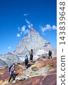 Group of four hikers climbs rugged multicolored rocks toward Matterhorn near Zermatt, Switzerland, showing active mountain tourism, teamwork and outdoor exploration in spectacular Swiss Alps scenery 143839648
