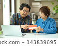 A couple in their 60s looking at their savings passbook in the living room 143839695