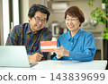 A couple in their 60s looking at their savings passbook in the living room 143839699