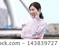 A middle-aged woman talking on her smartphone while walking in sportswear. 143839727