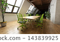 3D rendering of a modern attic conference room with a wooden table, green chairs, and slanted skylight windows. 143839925
