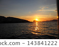 Sunset behind isolated rocky islet in Adriatic Sea with golden light on water 143841222
