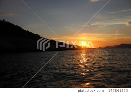 Wide open Adriatic Sea at golden sunset with silhouette rocky coast and sun reflection Wide open Adriatic Sea at golden sunset with silhouette rocky coast and sun reflection 143841223