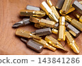 Heap of metallic steel and golden titanium screwdriver bits on a natural wooden background 143841286