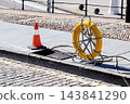 Fiber optic cable installation equipment on urban sidewalk next to open manhole 143841290