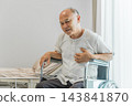 Senior man in wheelchair experiencing health issues in hospital setting. 143841870