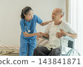 Female healthcare worker assisting senior man in wheelchair at hospital 143841871