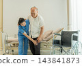 Nurse assisting elderly man with mobility in hospital room for recovery 143841873