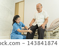 Healthcare professional assessing senior man's knee pain in clinic. 143841874