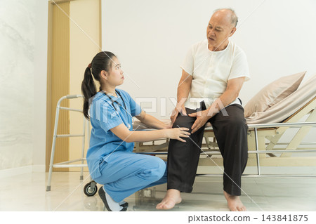 Nurse assisting senior man with knee evaluation in healthcare setting 143841875
