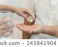 Caregiver administering medication to senior adult for health management 143841904