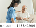 Senior man discussing medication with nurse in healthcare setting for wellness. 143841909
