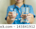 Healthcare professional administering medication with water in clinic 143841912