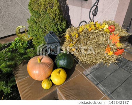 Autumn arrangement with pumpkins, hay, a lantern, and leaves 143842187