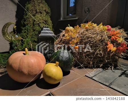 Autumn decor featuring pumpkins, hay, a lantern, and the moon Autumn decor featuring pumpkins, hay, a lantern, and the moon 143842188