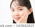 A young woman, appearing to be in her teens or twenties, with her hand on her cheek against a white background, smiling and looking directly at the camera in a beauty/glamour photo. 143842825