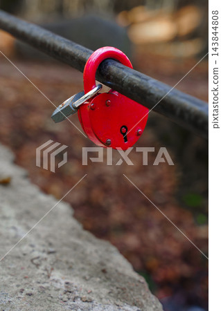 Red heart shaped padlock locked on a metal railing outdoor. Romance, marriage tradition and loyalty concept 143844808