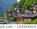 Hallstatt, Austria Alps Village Houses on Mountain Slope with Wooden Architecture and Green Forest Background 143844824