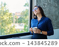 Mature tired, stressed businesswoman standing near window 143845289