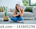 Serious young woman with smartphone sitting at home near sofa 143845298