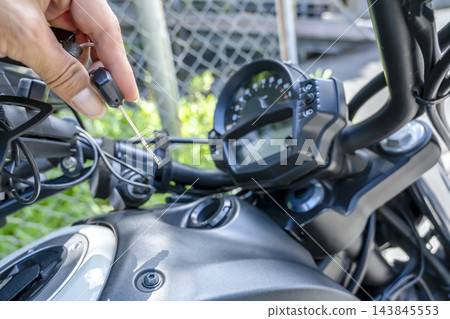 一隻男人的手將點火鑰匙插入一輛大型美式摩托車。 143845553