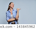 Smiling female student pointing finger aside at empty copy space on grey background 143845962