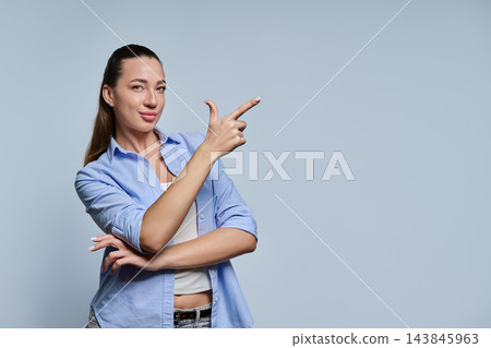 Young woman pointing finger at copy space in studio on gray background Young woman pointing finger at copy space in studio on gray background 143845963
