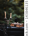 Old Book with Burning Candles and Black Raven - Gothic Still Life 143846135