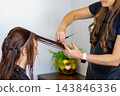 Close up of a professional hairdresser cutting a woman front hair with scissors in a beauty salon. Process of creating a modern haircut, hair styling concept. 143846336