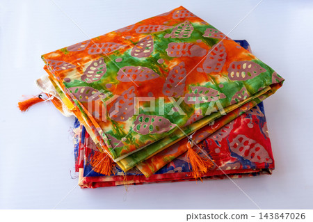 Folded colorful batik printed unstitched cotton three piece suit fabrics on white background. Traditional South Asian women clothing material. Folded colorful batik printed unstitched cotton three piece suit fabrics on white background. Traditional South Asian women clothing material. 143847026