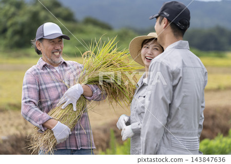 一男一女身穿工作服,邊說邊笑,一位老人手裡拿著一捆稻米。 一男一女身穿工作服,邊說邊笑,一位老人手裡拿著一捆稻米。 143847636