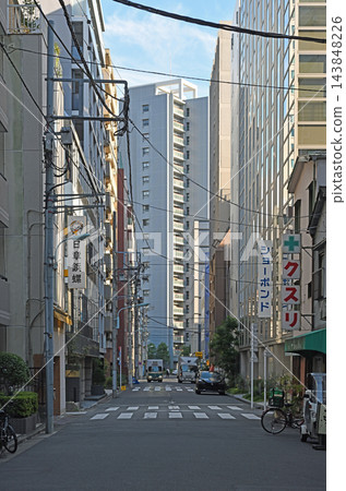一條小巷俯瞰日本橋箱崎町的摩天大樓;在辦公區的後巷裡,舊招牌和電線交錯,上演著日常的景象。 一條小巷俯瞰日本橋箱崎町的摩天大樓;在辦公區的後巷裡,舊招牌和電線交錯,上演著日常的景象。 143848226