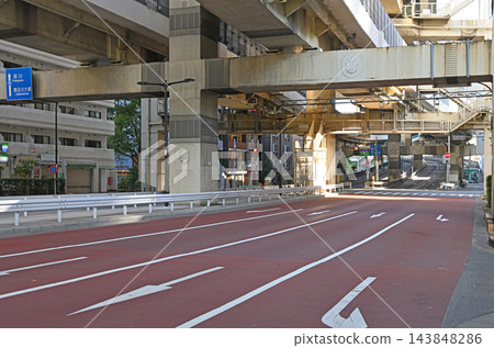 箱崎交叉口下方的紅色道路,以及橫跨的高架橋和白色箭頭,描繪了現代都市交通景觀。 箱崎交叉口下方的紅色道路,以及橫跨的高架橋和白色箭頭,描繪了現代都市交通景觀。 143848286