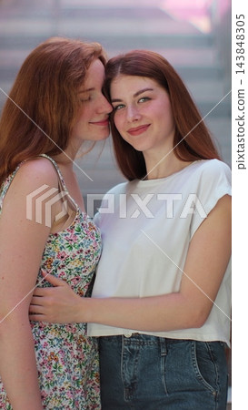 Vertical video. Two lesbian women standing on the street and hugging each other. Lgbt woman, showing love to each other. Happy lesbian relationships. 143848305