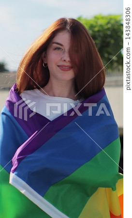Vertical video. Young woman covering herself in lgbt flag while walking on the street. Vertical video. Young woman covering herself in lgbt flag while walking on the street. 143848306