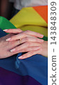 Vertical video. Close up lesbian couple in love holding hands on rainbow flag. Lgbt family holding hands outside. Woman relationship, lgbt family concept. 143848309