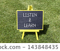 Listen and learn words symbol. Concept words Listen and learn on beautiful black blackboard. Beautiful green grass lawn background. Business listen and learn support concept. Copy space. 143848435