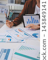 Business professional analyzing financial data on digital tablet dashboard with calculator and laptop, representing accounting software, ERP system integration, performance monitoring. 143849141