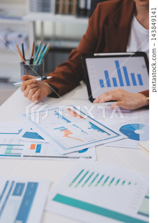 Business professional analyzing financial data on digital tablet dashboard with calculator and laptop, representing accounting software, ERP system integration, performance monitoring. Business professional analyzing financial data on digital tablet dashboard with calculator and laptop, representing accounting software, ERP system integration, performance monitoring. 143849141