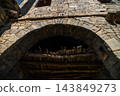 Stone masonry archway with wooden ceiling supports 143849273