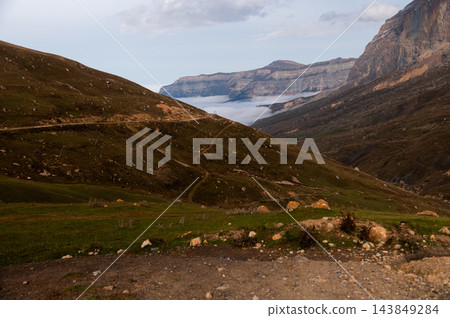 Mountain landscape with winding road and clouds in valley Mountain landscape with winding road and clouds in valley 143849284