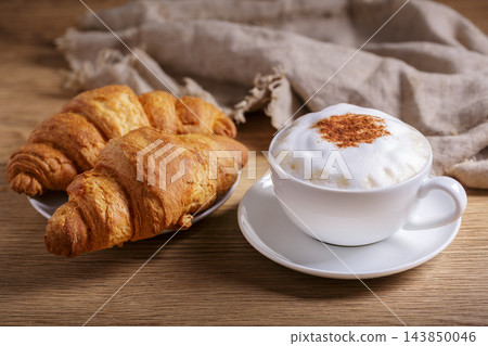 cup of cappuccino coffee with croissantc on wooden table 143850046