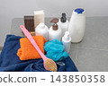 Set for washing body and hair in the bathroom. Towel and brush washcloth, Bottles of shampoo, lotion and liquid soap. Shower gel. 143850358
