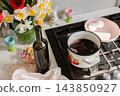 A pot, red wine, and a bowl of eggs sit on a stove in a home kitchen, ready for dyeing eggs as part of an Easter holiday activity 143850927