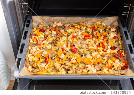 Eggplant, zucchini, carrots, onions, garlic, cauliflower, and peppers bake on a tray in an oven during meal preparation at home Eggplant, zucchini, carrots, onions, garlic, cauliflower, and peppers bake on a tray in an oven during meal preparation at home 143850934
