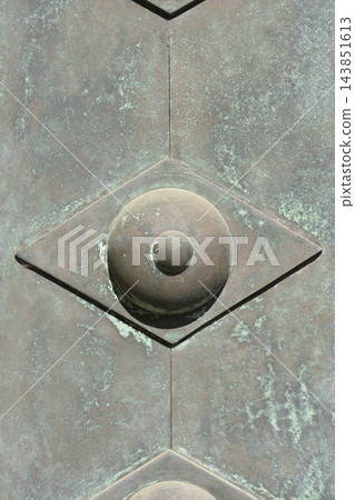 Decorative metal rivet on weathered bronze door texture 143851613